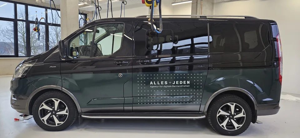 Dunkler Van mit grüner Teilfolierung und weißem ALLES+JEDEN-Logo
