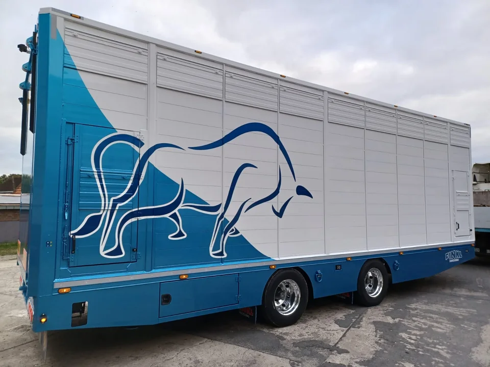 Weiß-blauer Tiertransport-Auflieger mit großem Stiermotiv