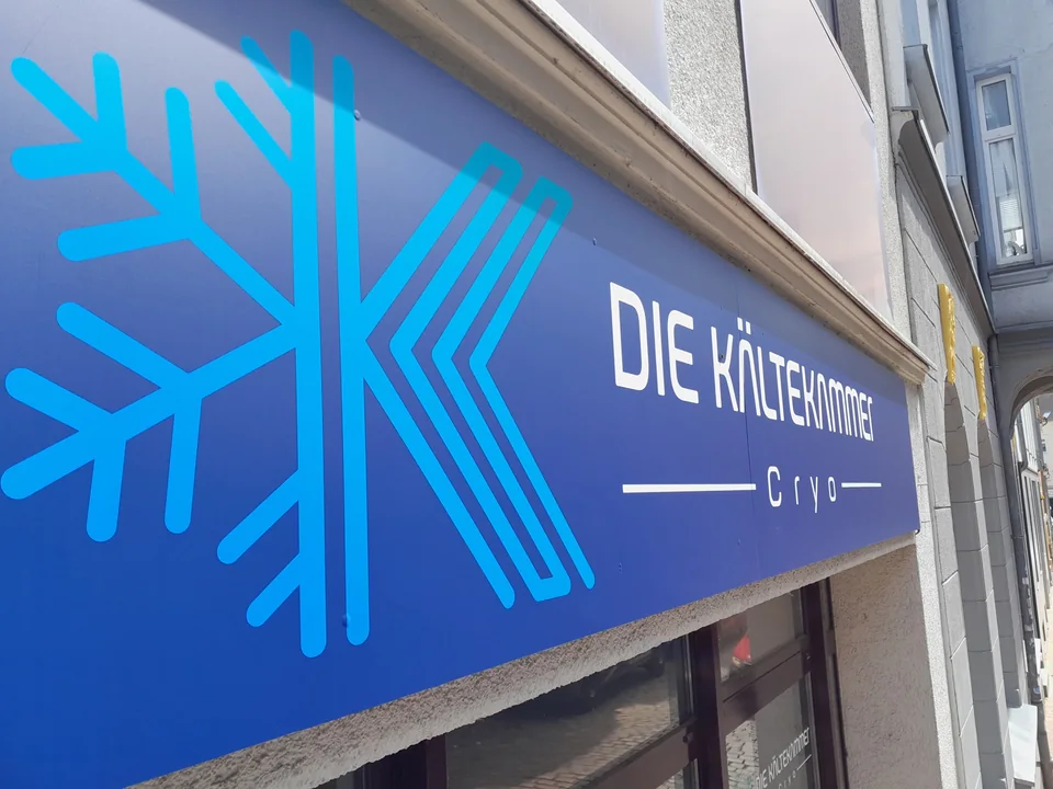 Blaues Firmenschild Die Kältekammer mit türkisfarbenem Schneeflockenmotiv an einer Fassade